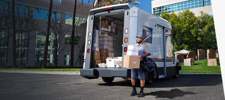 Letter carrier ready to deliver packages unloaded from the back of a 美国邮政总局 Next-Generation Delivery Vehicle.